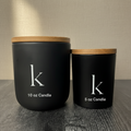 Two matte black candles with wooden lids representing size difference.